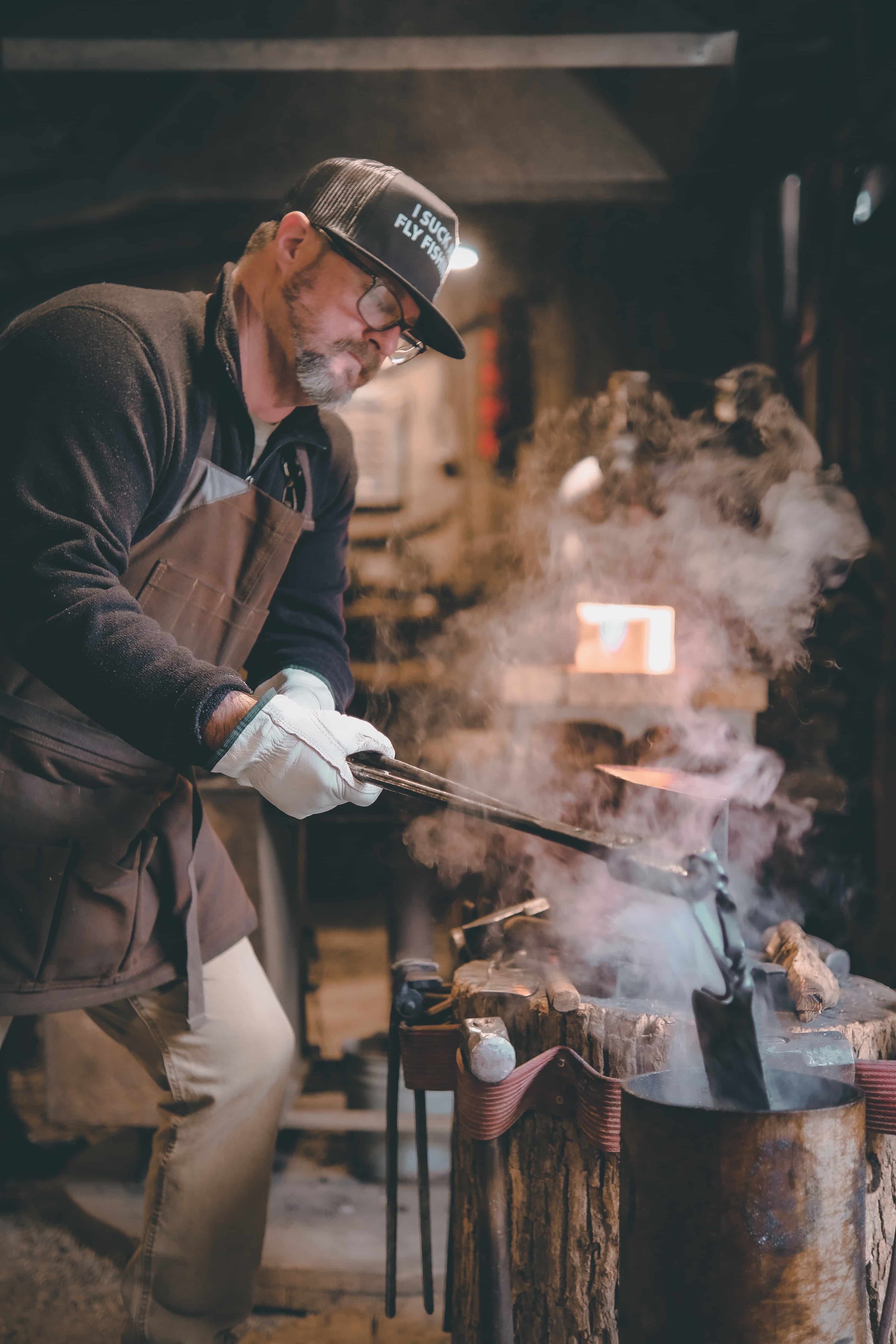 Smith brushing steel on anvil