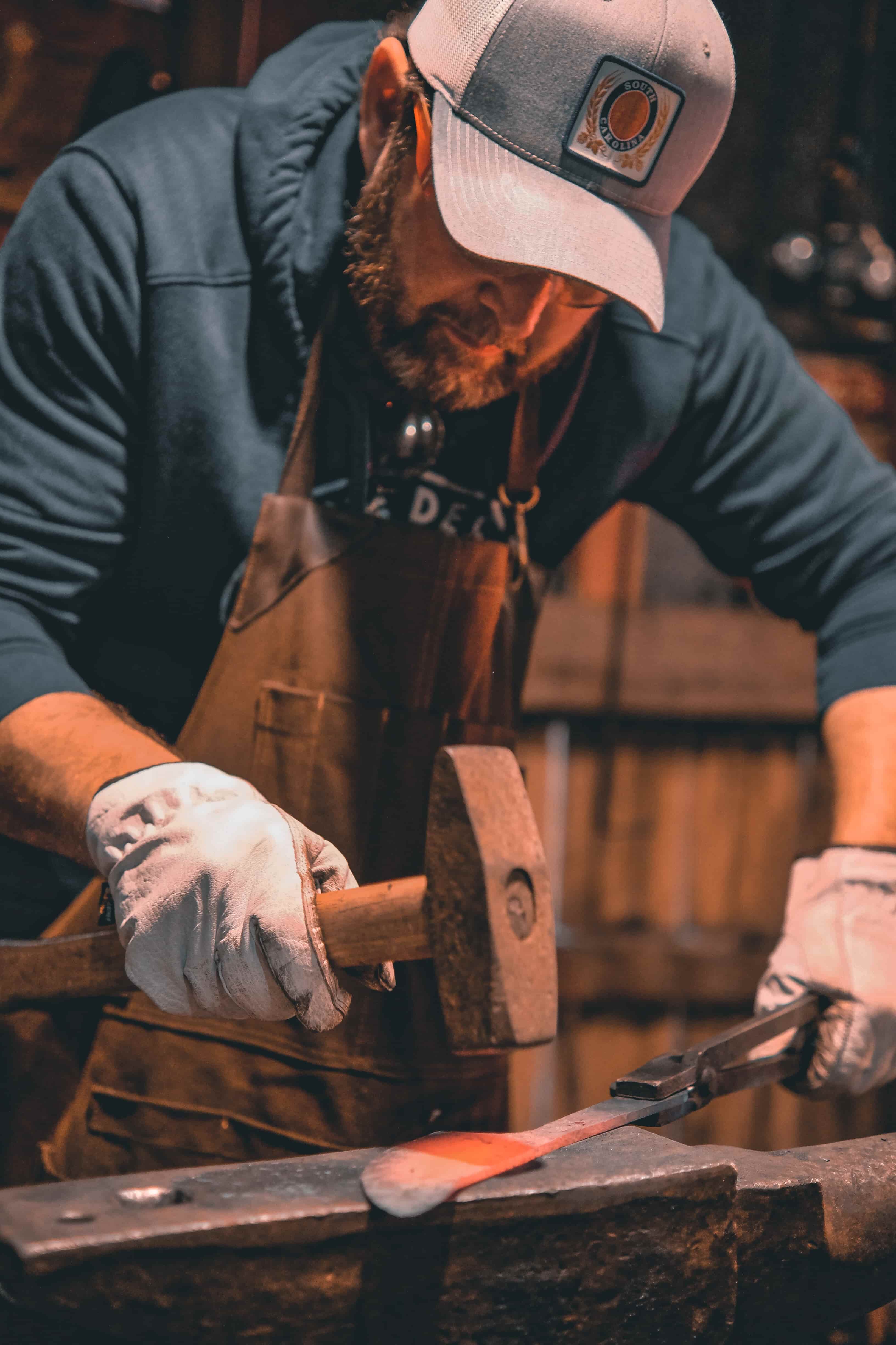 Hammer striking glowing steel on the anvil at The Forge